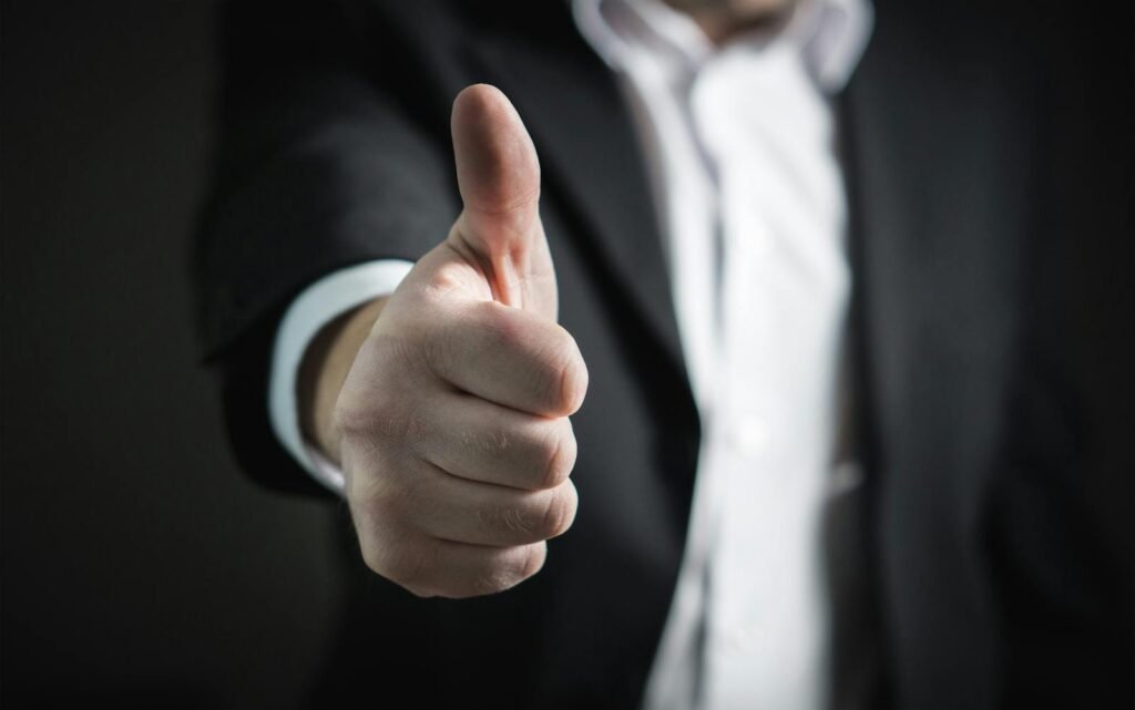 A close-up of a man's thumbs up gesture, symbolizing success and agreement.