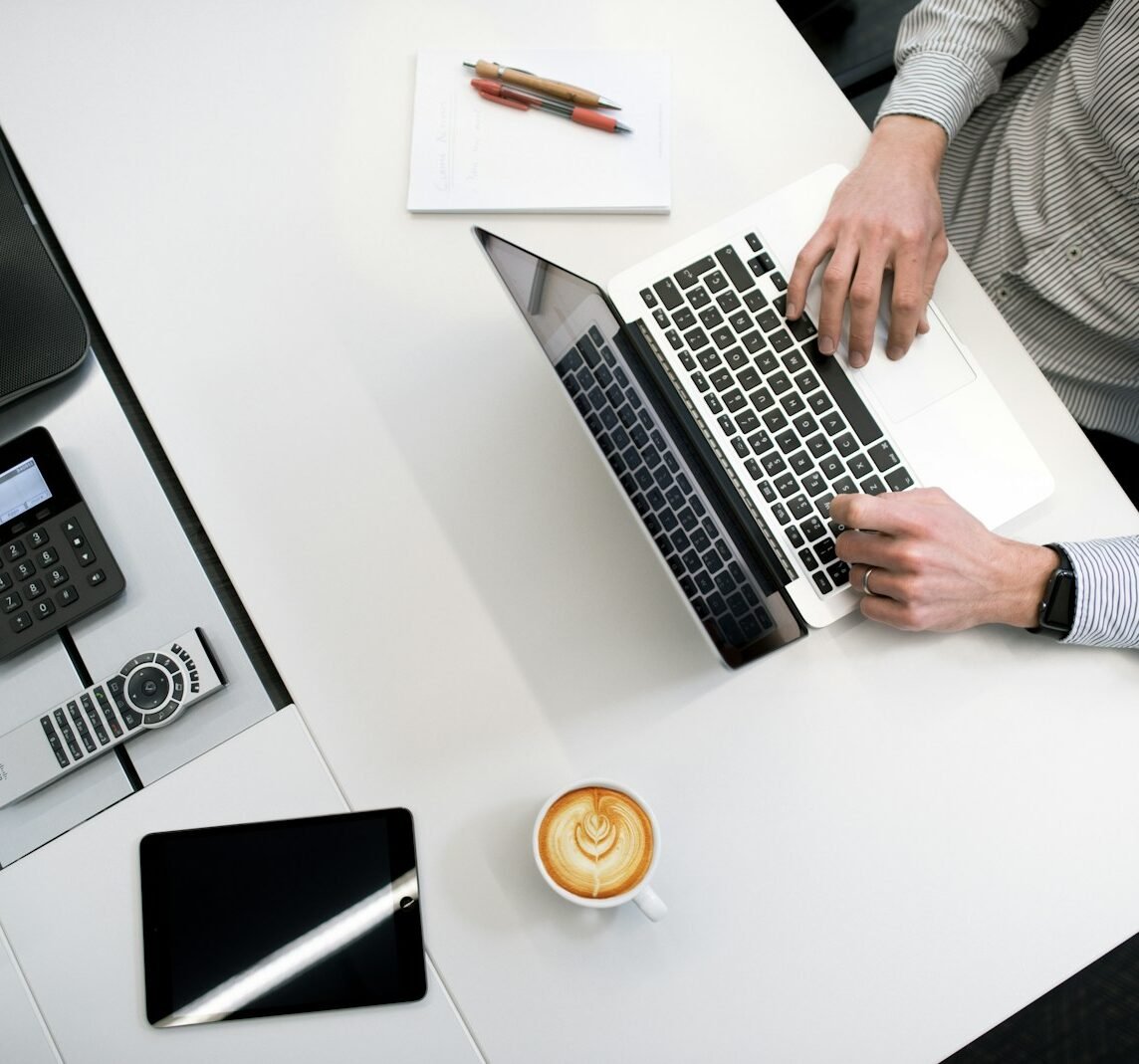 person using laptop on white wooden table